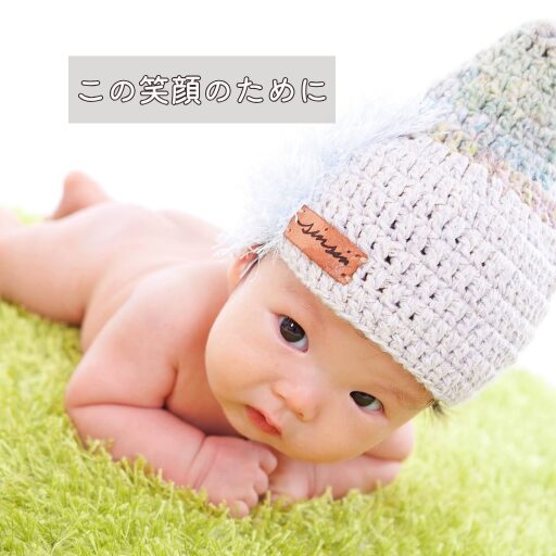 『この笑顔のために』というキャプション付きの、白い帽子をかぶった赤ちゃんの写真。未来への希望を象徴